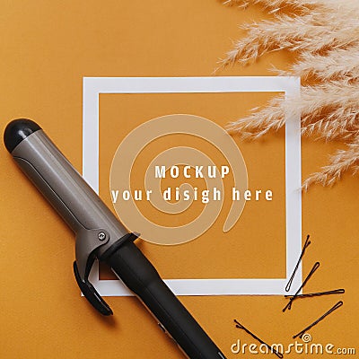 Hairdresser tools: curling iron and bobby pins over orange. Top view Stock Photo