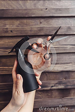 Hairdresser tools on a wooden background in the hands of a master. Protective spray and hair scissors. Professional hairdresser Stock Photo