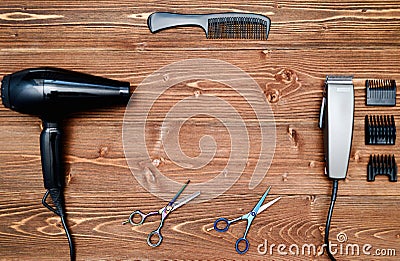 Hairdresser tools on wooden background. Top view on wooden table with scissors, comb, hairclipper and hairdryer, free space. Stock Photo