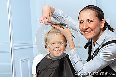 Hairdresser woman discuss how to cut forelock of the little boy Stock Photo