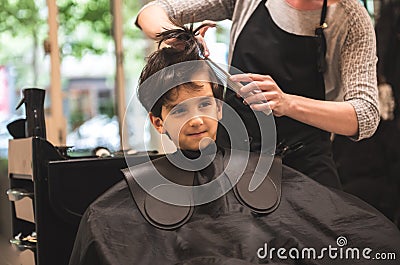 Hairdressers hands making hairstyle to child little boy in the barber shop hair cut professional - Little boy in the barber shop Stock Photo