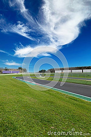 Hairpin bend and turn exit with curb and green field on motor sport circuit asphalt track Stock Photo