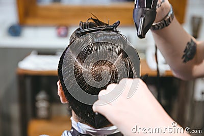 Hairstylist drying hair of male client using hairdryer and comb Stock Photo