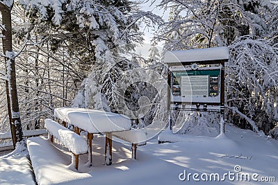 Rest area with table and benches and tourist information board, winter, Hala Slowianka, Poland Editorial Stock Photo