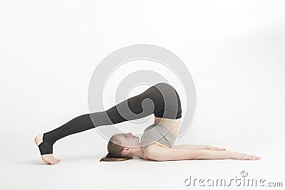 Halasana. Plow Pose. Young woman during a yoga class. Side view. Yoga trainer shows technique of performing asana on white Stock Photo