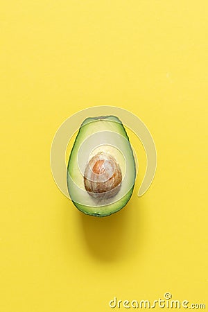 Half avocado on pastel yellow background. Minimalism Stock Photo
