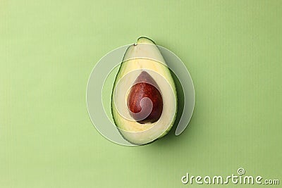 Half avocado with seed on a green background top view Stock Photo