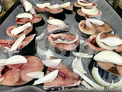 Half Cut Raw Bonito Fish Fillet Slices with Onion in Oven Tray Ready to Bake. Stock Photo