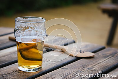 Half drunk pint of lager with a wooden spoon in the background i Stock Photo