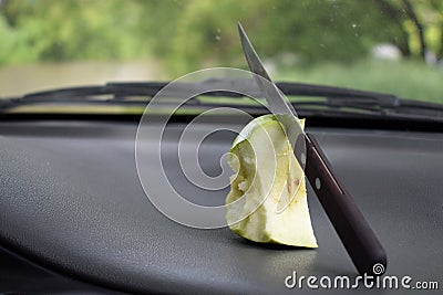 Half-eaten apple with a knife lies in the car near the windshield Stock Photo