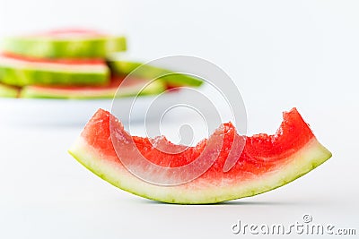 A half eaten slice of watermelon with a pile of watermelon slices in behind. Stock Photo