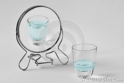 Half-empty water glass looking in the mirror and seeing himself as a full glass - Concept of optimism Stock Photo