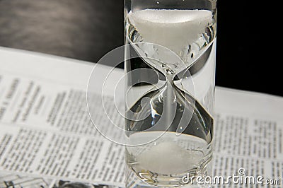 Half-filled sandglass on newspaper Stock Photo