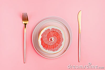 Half a grapefruit on a pink plate on a pastel background Stock Photo