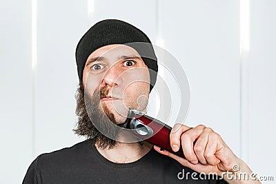 Before - after and half hair. Handsome bearded man trimming his beard with a trimmer Stock Photo