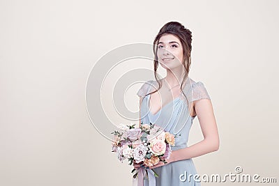 Half length beautiful female model holding a bouquet of flowers wearing in luxurious long lacy dress isolated on background Stock Photo