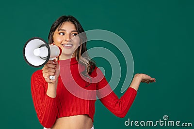 Half-length portrait of young beuatiful girl, student in casual style clothes with megaphone isolated on green studio Stock Photo
