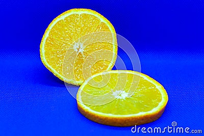 Half an orange and a slice in a section on a dark blue background. Healthly food. Stock Photo