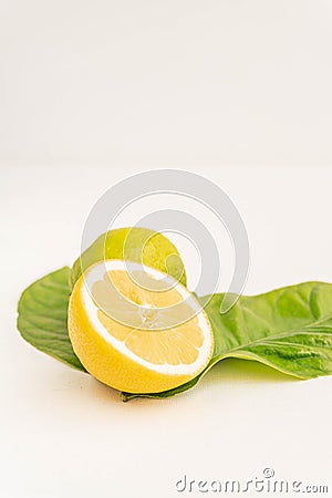 Half Organic Lemon with two lemon tree leaves and a lime isolated on white. Close up view. Fresh summer. Stock Photo