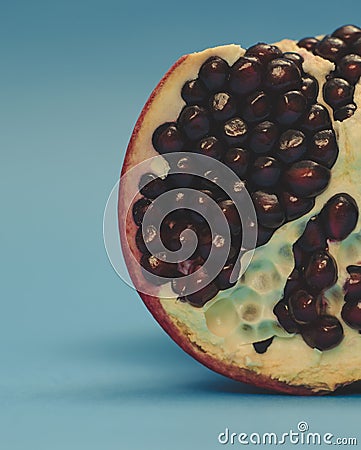 Half pomegranate on a blue background close-up. Ripe pomegranate seeds Stock Photo