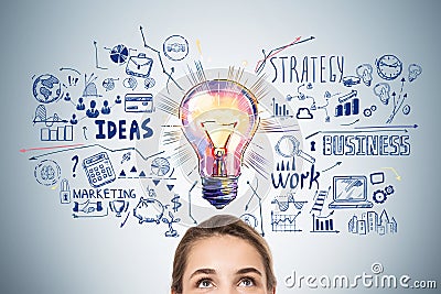 Half portrait of businesswoman looking up at colorful lightbulb Stock Photo