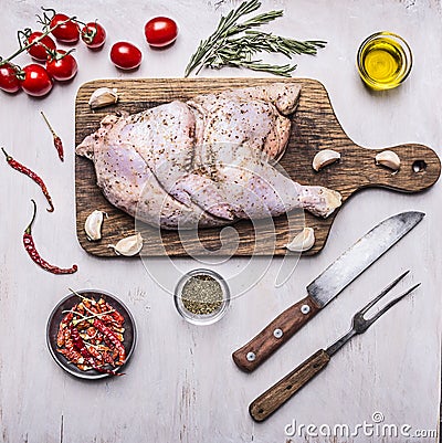 Half raw chicken,Ingredients for cooking, tomatoes, knife and fork for the meat, peppers wooden rustic background top view Stock Photo