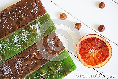 Half a red orange, oriental delicacy - sudzhuk and hazelnuts on a white surface of painted boards Stock Photo