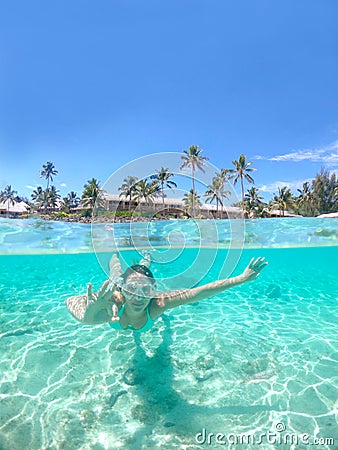 HALF UNDERWATER: Woman snorkeling away from oceanfront resort gives the ok sign. Stock Photo