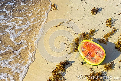 Half watermelon lies on the beach and in water waves Stock Photo