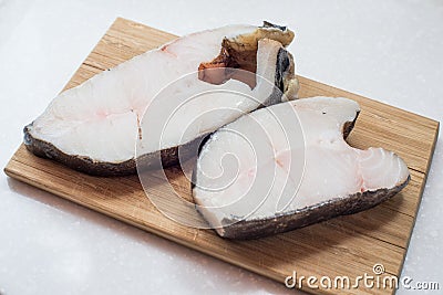 Halibut fish steak on a chopping Board Stock Photo
