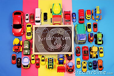 Ð¡halkboard with the inscription: Kindergarten, surrounded by colored cars on multicolored background Stock Photo