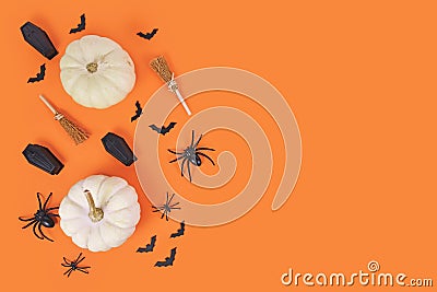 Halloween arrangement with white pumpkins, black spiders, bats and coffins and witch brooms on orange background Stock Photo