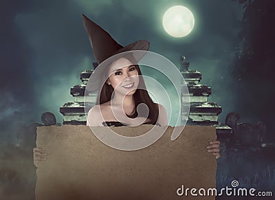 Halloween asian witch with hat holding blank paper Stock Photo