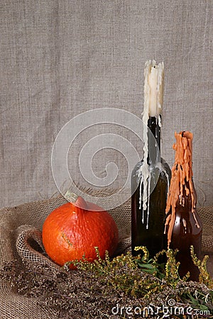 Halloween autumn still life. Pumpkin, candles in bottles, herbs. Light canvas background Stock Photo