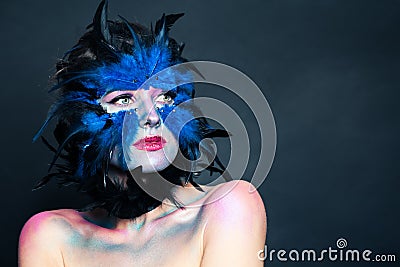 Halloween character portrait. Woman with creative blue bird makeup on dark background Stock Photo