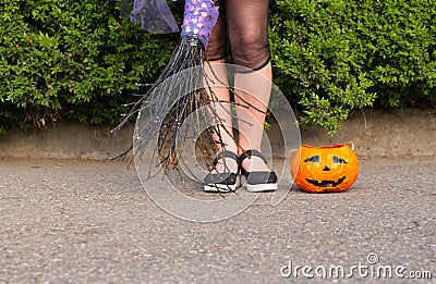 Halloween closeup witch legs in boots and with broomstick and pumpkin. Stock Photo