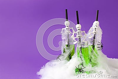 Halloween composition with festive drink, toxic green cocktail with scary party decor skeleton and spiders, spider web on Stock Photo