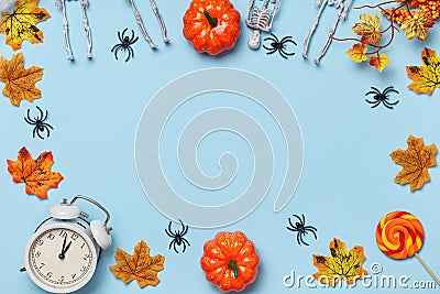 Halloween composition frame. Skeletons pumpkin spiders alarm clock autumn leaves. Decor on a blue background Stock Photo