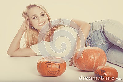 Halloween concept, happy Girl lies on floor with pumpkins preparing for holiday, with Jack lantern, funny and spooky pumpkin. Stock Photo