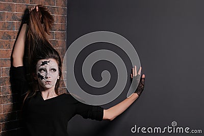 Halloween concept of makeup for All Saints or the Dead. The girl is holding herself with one hand by her hair, while the other is Stock Photo