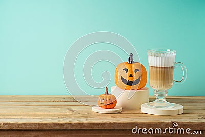 Halloween creative concept with latte macchiato coffee cup and pumpkin decor on wooden table Stock Photo