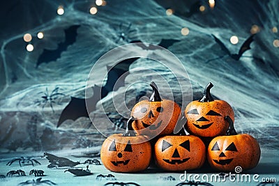 Halloween decoration with funny pumpkin heads, spider, web and flying bat on mystical bokeh background. Stock Photo