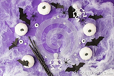 Halloween decorations. Decorative white pumpkins, bats, eyes, skeletons, creepy straws for cocktail on purple background. Stock Photo