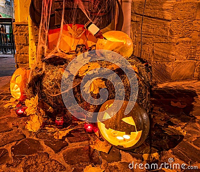 Halloween decorations - Jack-o'-lanterns - carved pumpkins, burning candles, hay bale, fallen maple leaves Stock Photo