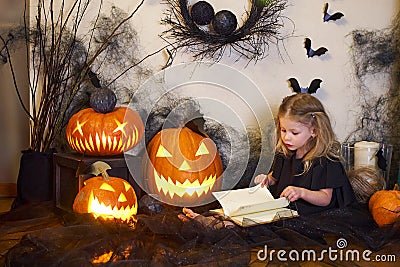 Halloween girl reads book spells. Blonde witch. Magic wand in hands of magician. Stock Photo