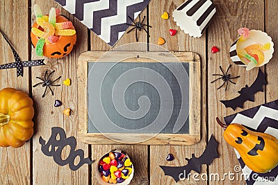 Halloween holiday background with chalkboard, pumpkin and candy. Stock Photo