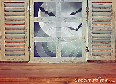 Halloween holiday concept. Empty rustic table in front of haunted night sky background and old window. Ready for product display m Stock Photo