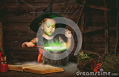 Halloween. little witch child cooking potion in cauldron with Stock Photo