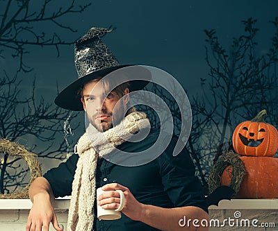 Halloween macho holding cup at window with autumn trees Stock Photo