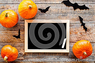 Halloween mockup. Chalkboard near paper bats and pumpkins on wooden background top view Stock Photo